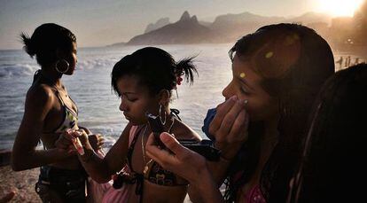 Unas adolescentes se maquillan en la playa de Copacabana.