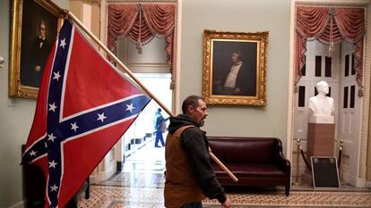 Un partidario del presidente Donald Trump lleva una bandera de batalla confederada en el segundo piso del Capitolio de los EE. UU. 