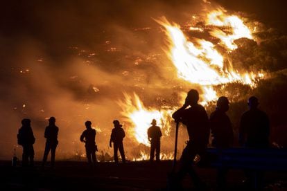 Bomberos forestales y vecinos de la zona observan las llamas en el incendio forestal del pasado agosto en Navalacruz, en Ávila.