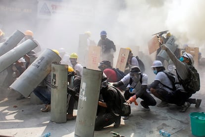 Manifestantes se protegen durante los enfrentamientos con la policía, en Yangón (Myanmar), este domingo.