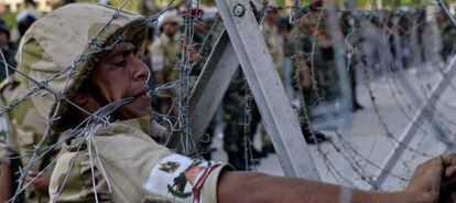 Un soldado de la Guardia Republicana instala alambre de espino alrededor del cuartel de El Cairo donde est&aacute; detenido Mohamed Morsi.