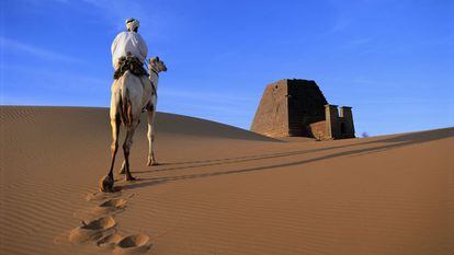 Un hombre monta a camello en el desierto.