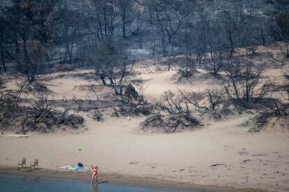 Una mujer juega a la pelota en la orilla de una playa afectada por los incendios forestales en Glystra, en la isla de Rodas, este jueves. 