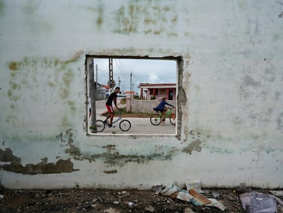 Niños en bicicleta pasan frente a un edificio abandonado en Isabela de Sagua, Cuba el 28 de enero 2023