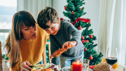 Cute little boy and his beautiful mother having fun during Christmas dinner or lunch.