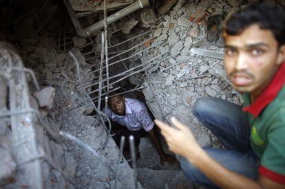 Un hombre se introduce entre los escombros para buscar supervivientes en el derrumbe del edificio de ocho plantas en Savar, en las afueras de Dacca (India).