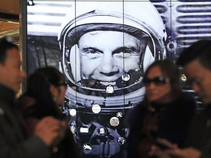 Un gurpo de turistas frente a un retrato del astronauta John Glenn.