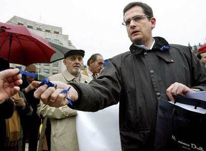 El presidente del PP en Vizcaya, Antonio Basagoiti, reparte lazos azules durante la concentración en Bilbao