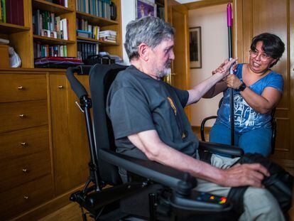 Una empleada del hogar atiende a un hombre en silla de ruedas en Madrid.