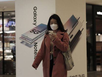 Una mujer consulta su móvil frente a una tienda de Samsung en Seúl. 