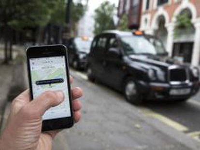 Un usuario utiliza la aplicaci&oacute;n de Uber frente a una parada de taxis de Londres. 