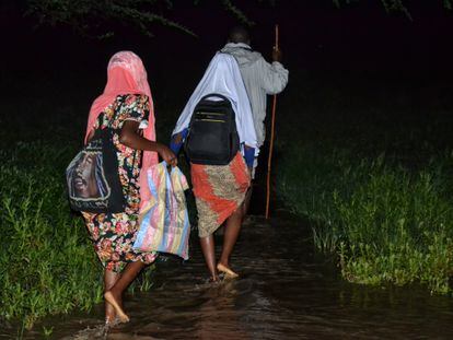 Las hermanas Nchira cruzan un río rumbo a la escuela, acompañadas de su padre.
