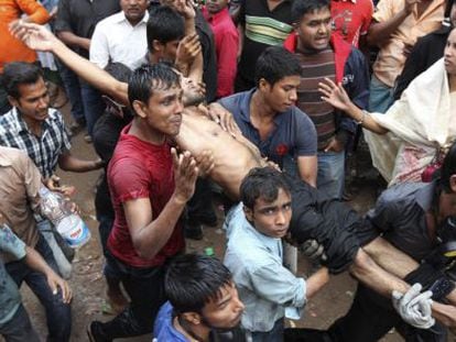 Un grupo de personas carga con un herido en el incendio de una f&aacute;brica textil en las cercan&iacute;as de Daca, Bangladesh. 