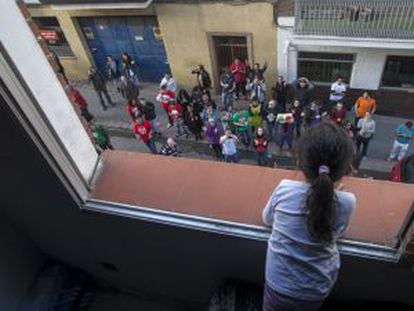 Una niña mira desde la ventana a un grupo de manifestantes que protesta contra el desahucio de su familia