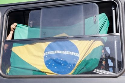 Un partidario de Bolsonaro exhibe una bandera de Brasil en un autobús tras ser desmontado el campamento de bolsonaristas que se había levantado enfrente del cuartel general del Ejército, en Brasilia.