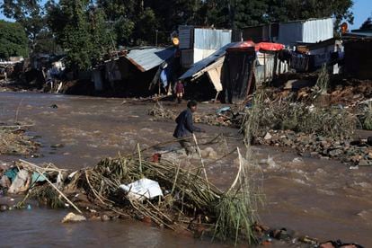 A man crosses a river in an informal settlement during flooding in Durban, South Africa.