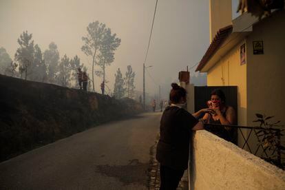 Vecinas de Cruzinha, Alvaiazere (centro de Portugal) se protegen contra el humo, mientras los bomberos trabajan en las labores de extinción el domingo 10 de julio.  