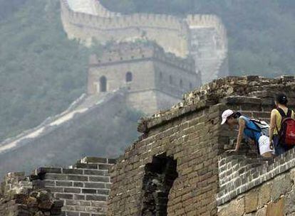 Dos turistas observan una zona dañada de la Gran Muralla china.