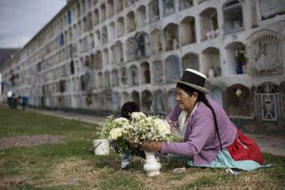 Una mujer peruana adorna con flores la tumba de un familiar.