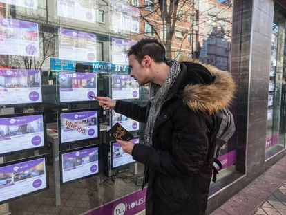 Un joven toma nota de pisos en venta en una agencia inmobiliaria en Madrid. 