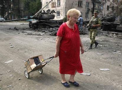 Una mujer camina por una calle de Tsjinvali con sus pertenencias en una caja durante la guerra de agosto.
