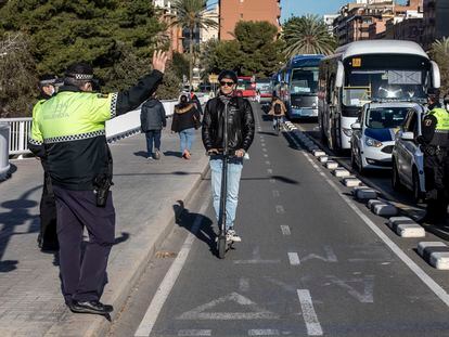 Dos agentes de la Policía Local paran a un ciudadano en patinete en Valencia.