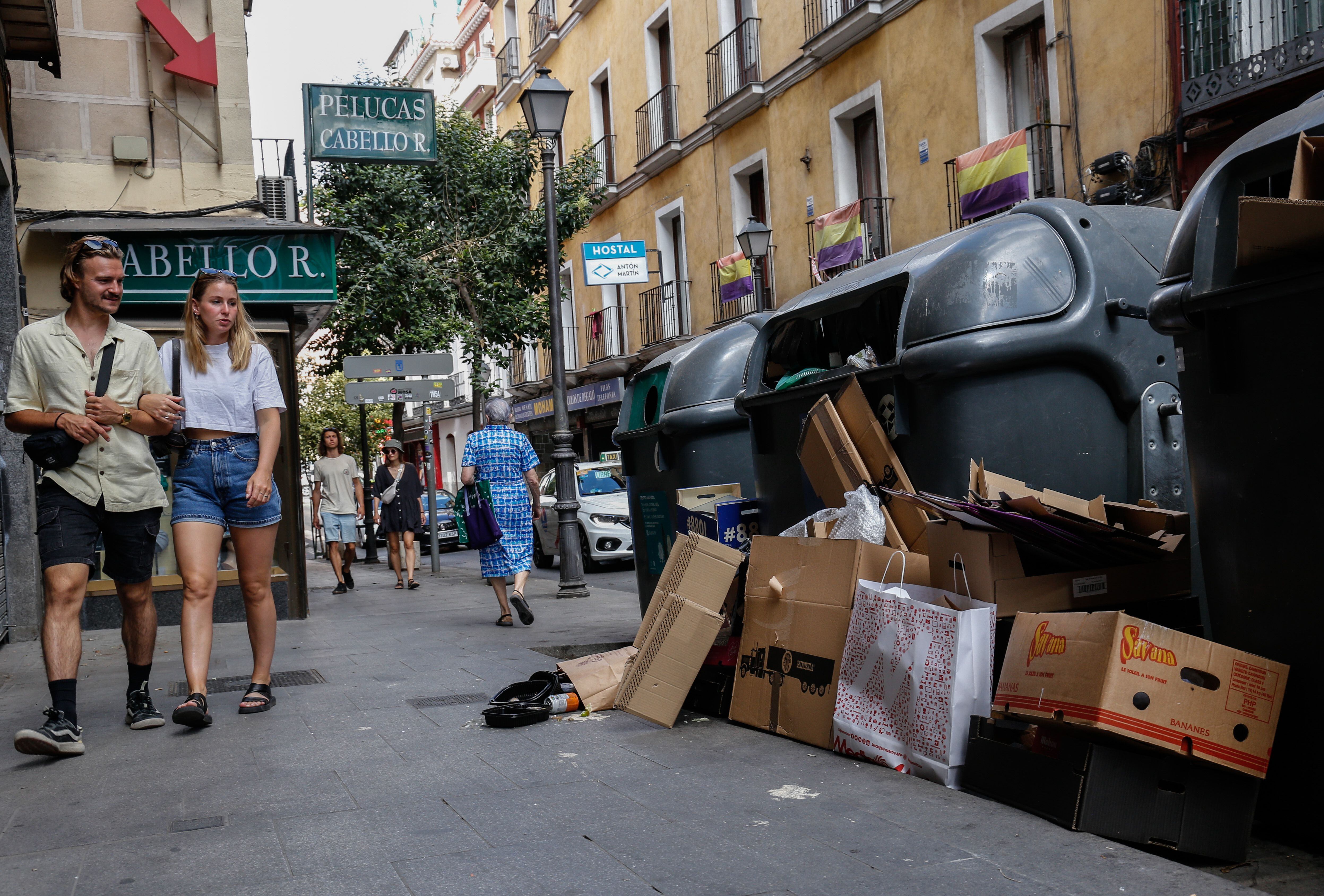 Una pareja mira los residuos que hay fuera de los contenedores en la calle de la Magdalena de Madrid, este lunes.