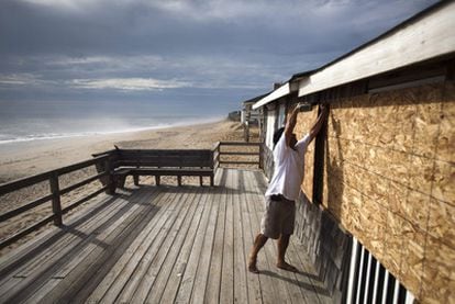 Un hombre coloca tablones de madera para proteger las ventanas de una casa en Kitty Hawk, Carolina del Norte, unas horas antes de que el huracán Irene toque tierra en esa región de EE UU