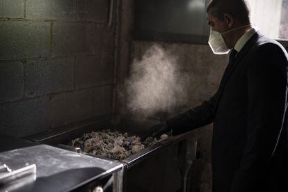 Un trabajador del tanatorio recoge las cenizas de una víctima de covid-19 tras la incineración de sus restos, en el tanatorio Memora en Girona, el 19 de noviembre de 2020.