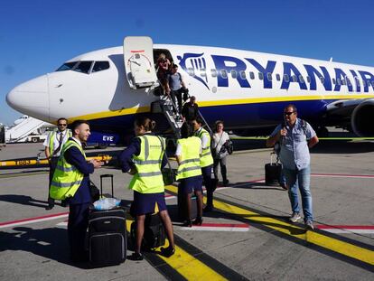 Tripulantes de cabina de pasajeros de Ryanair, a pie de pista, ante un avi&oacute;n de la compa&ntilde;&iacute;a.