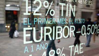 Viandantes reflejados en un escaparate de una entidad bancaria, en Bilbao, con una oferta de depósitos.