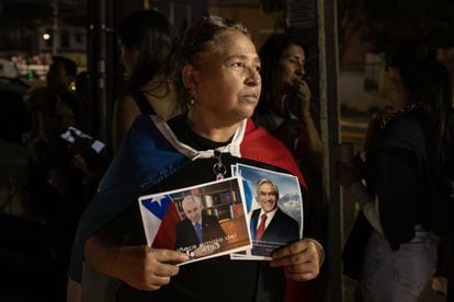 Una mujer sostiene fotografías del expresidente Sebastián Piñera, afuera de la sede del partido Renovación Nacional.