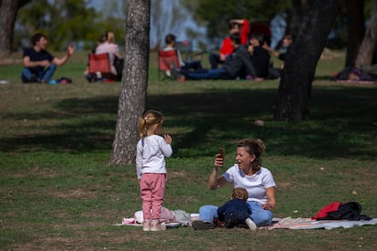 Una mujer con dos niños toma fotos alejada de otros grupos en la Casa de Campo en Madrid.