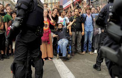 Manifestantes se encaran a la policía tras el inicio del desmantelamiento del campamento situado en la plaza Cataluña.