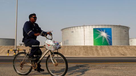 Un empleado pasa en bicicleta cerca de un tanque de petróleo de Aramco, la petrolera estatal saudí.