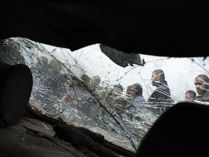 Un grupo de palestinos a través del cristal roto de un coche alcanzado por una bomba israelí.
