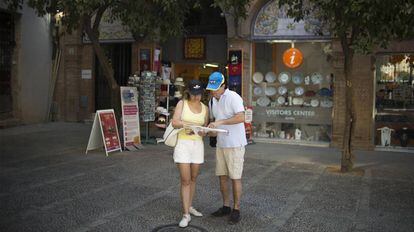 Una pareja consulta un mapa en Sevilla, frente a un punto de información turística.