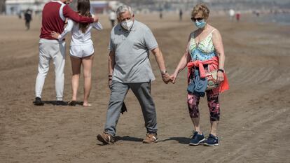 Una pareja mayor pasea por la playa de la Malvarrosa de valencia.