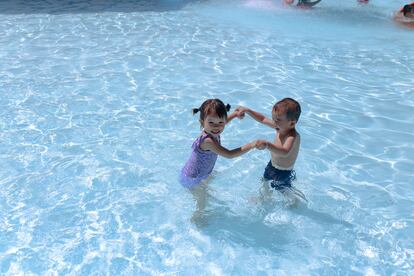 Dos niños juegan en una piscina.
