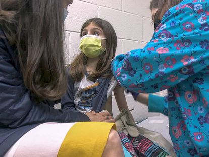 Alejandra Gerardo, de nueve años, mira a su madre mientras la vacunan contra la covid en el hospital universitario de la Universidad de Duke (EE UU).