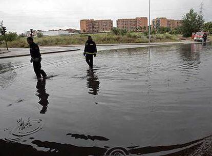 Dos bomberos observan la inundación en la rotonda de Fuente Carrantona, en Moratalaz. Abajo, atasco junto al Arco del Triunfo.
/ R. GUTIÉRREZ