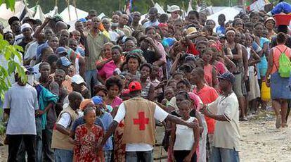 Miembros de la Cruz Roja tratan de ordenar las filas de refugiados en el campamento de Nancharles antes de repartir ayuda.