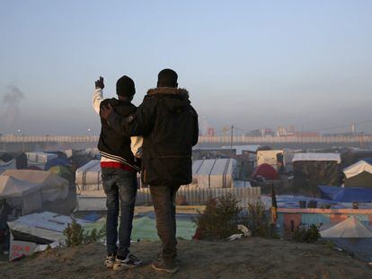 Dos personas observan las tiendas del campamento de Calais durante el segundo día de evacuación. 