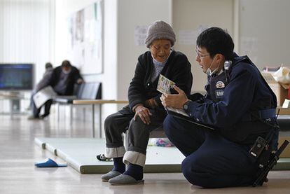Un policía japonés pregunta a una anciana que se ha tenido que trasladar a un centro de evacuación de Iwaki, en la prefectura de Fukushima, debido a la zona de exclusión aérea establecida alrededor de la central.