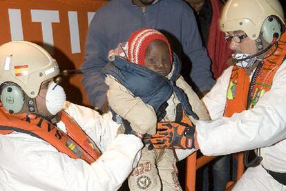 Miembros de Salvamento Marítimo trasladan a uno de los niños que viajaban en la embarcación.