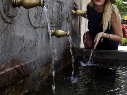 Una mujer se refresca en una fuente del centro de Granada en plena ola de calor por la masa de aire africano.
