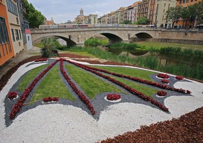 Muntatge de flors que representa la Cocollona, una bèstia de la tradició gironina que és un animal meitat cocodril i meitat papallona. Al fons es veu el Pont de Pedra i la Catedral de Girona.