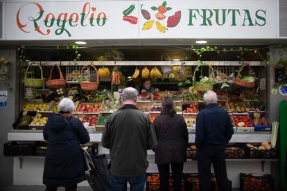 Varias personas esperan su turno en una frutería del mercado del Arenal en Sevilla, este viernes.