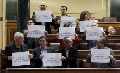 El coordinador general de IU, Cayo Lara y otros diputados de su grupo muestran carteles con el lema "Yo también soy el enemigo" en el Congreso.
