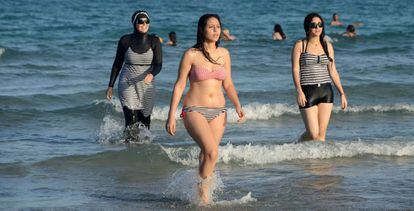 Mujeres tunecinas vistiendo burkini (izquierda), bikini (centro) y bañador en las playas de Bizerta.